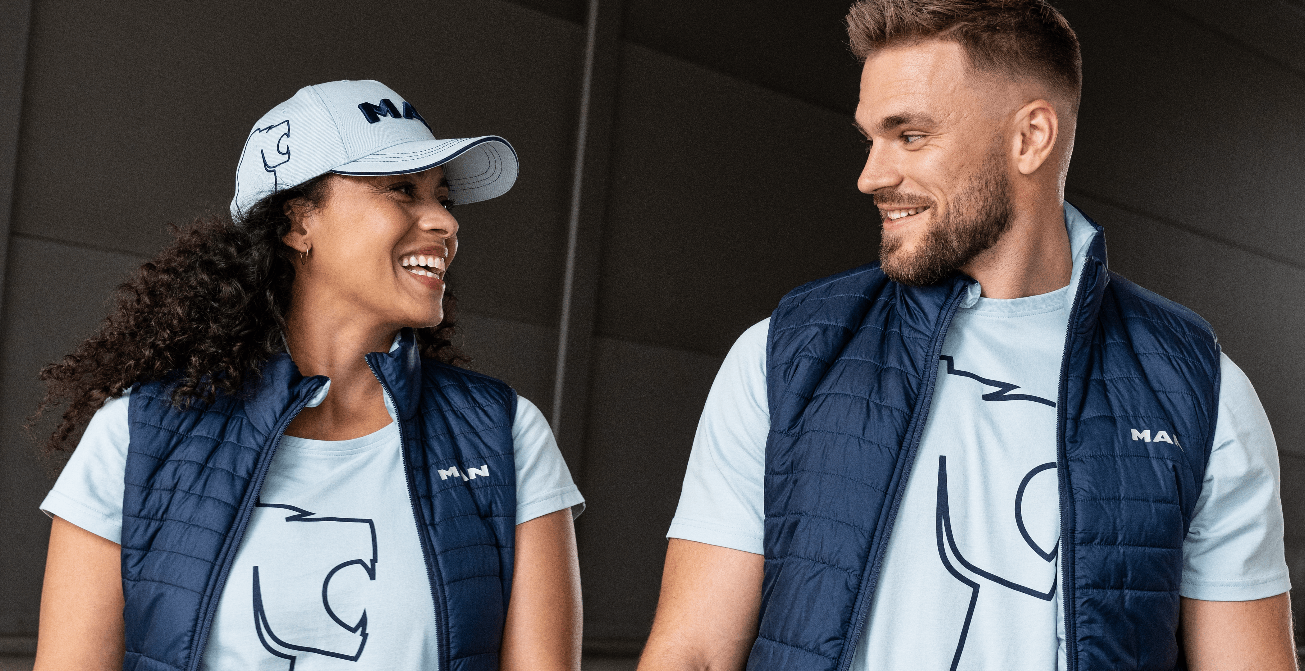 Lachendes Paar in MAN-Lion-Collection-Westen und T-Shirts, ideal für einen sportlichen und stylischen Look im Alltag.